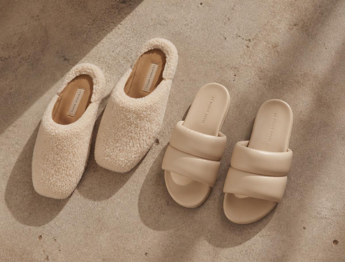 Two pairs of minimal slippers arranged overhead on warm concrete
